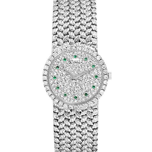 The watch is a Piaget 9706 Women's White Gold  9706 Women's White Gold  9706 model viewed from the top, showing its White Gold Pave Diamond Emerald dial and intricate bracelet.